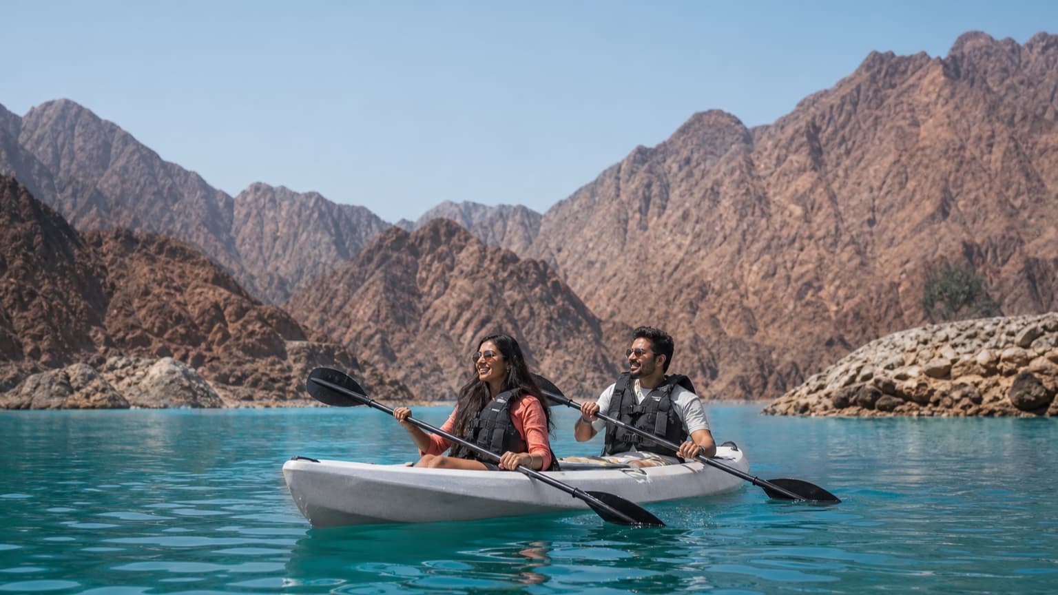 Indian couple overlooking turquoise Hatta Dam and the Hajar Mountains